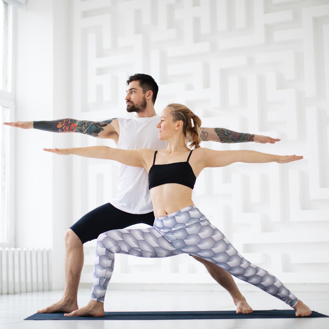 un homme et une femme réalisent la posture de yoga guerrier 2